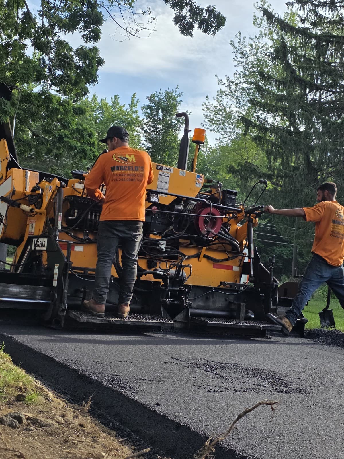 Asphalt paver machine laying a new surface with the crew