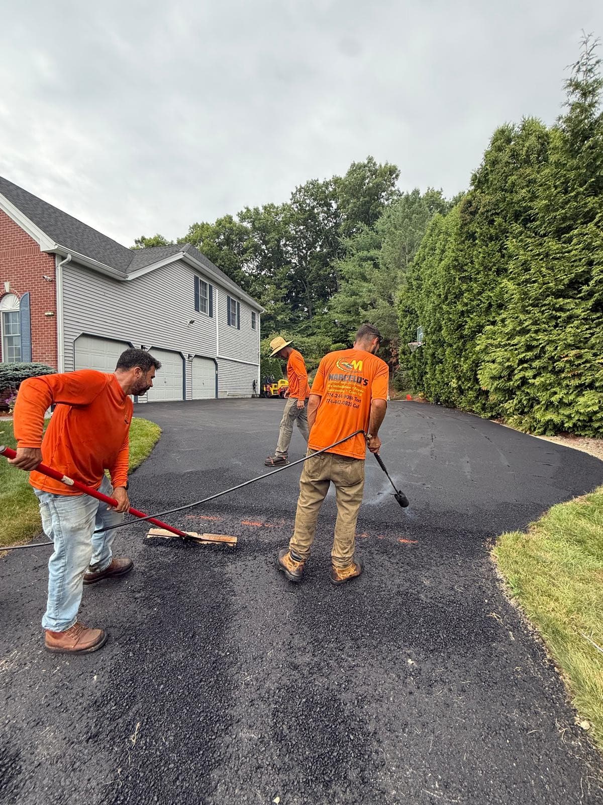 Crew applying fresh sealer to a curved residential driveway