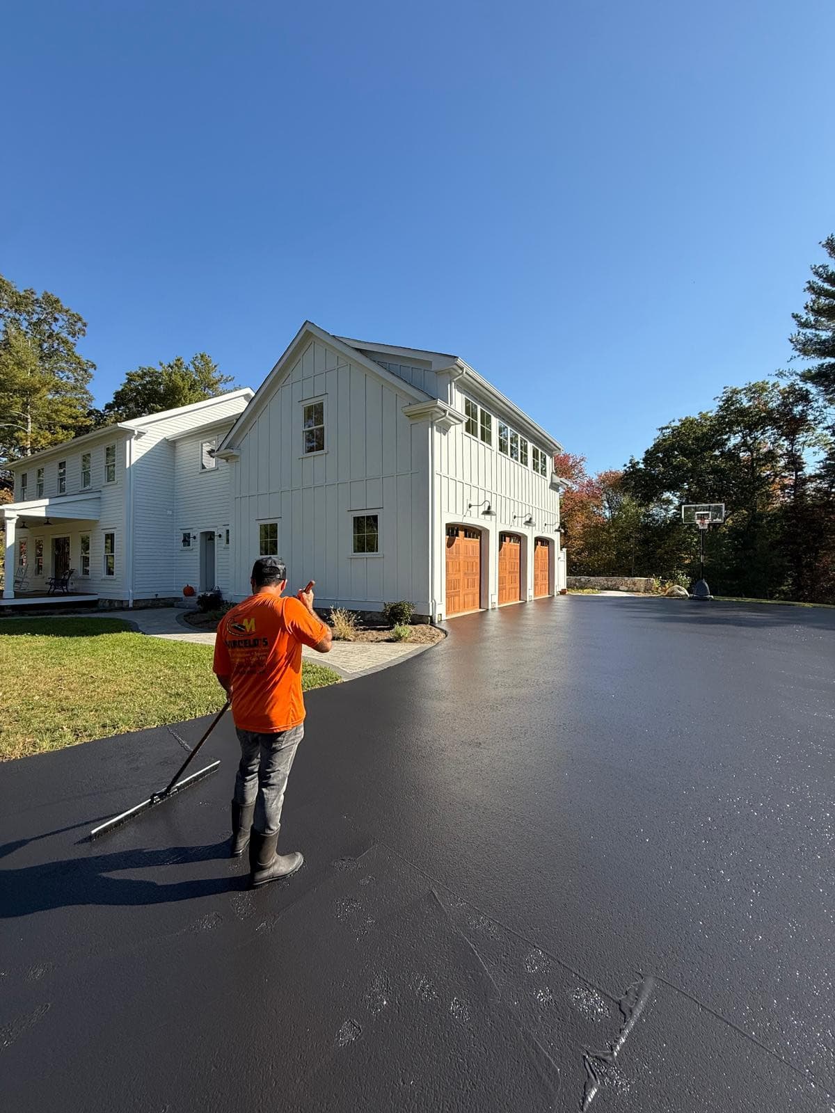 Marcelo Asphalt crew sealcoating a residential driveway in Central MA