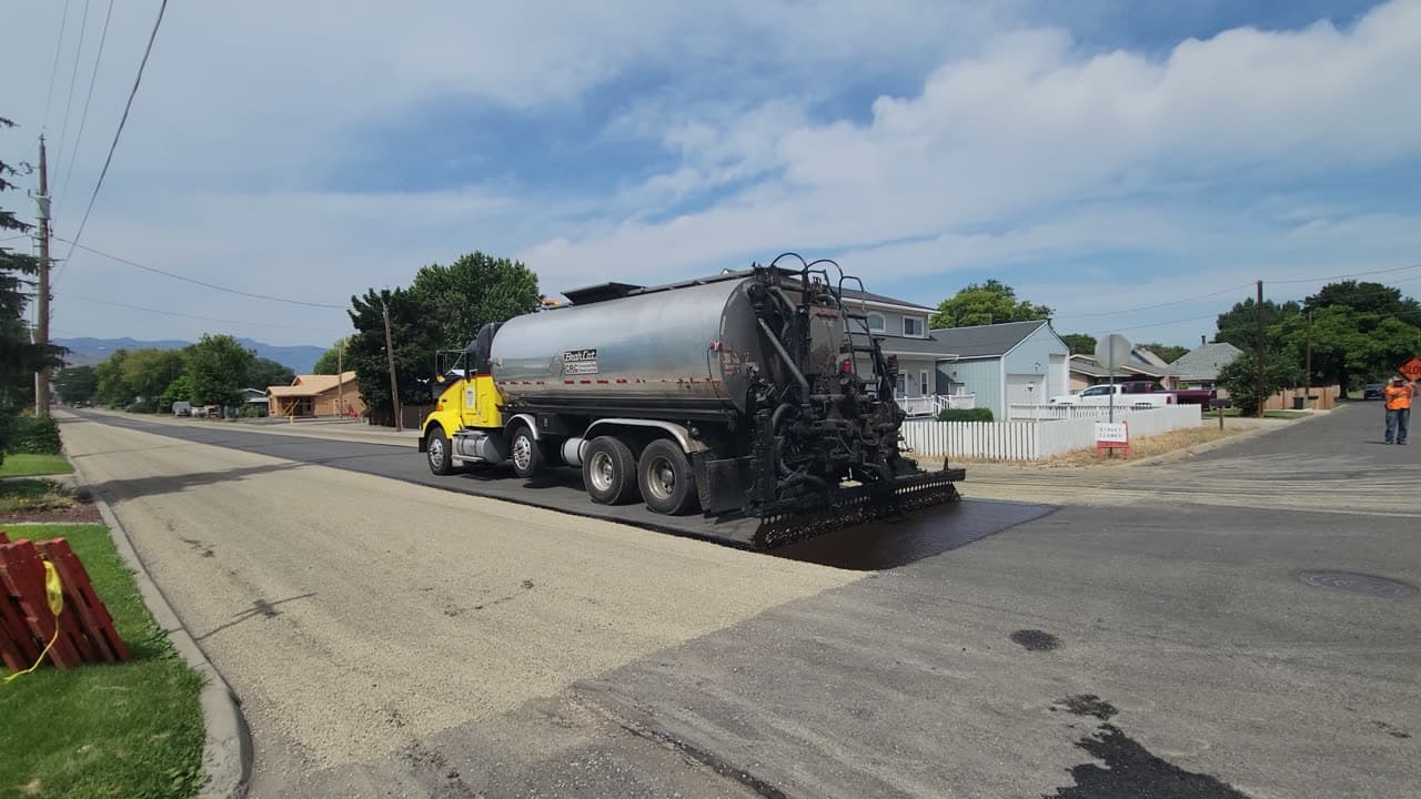 Freshly sealcoated residential asphalt driveway with a clean, dark finish in Massachusetts