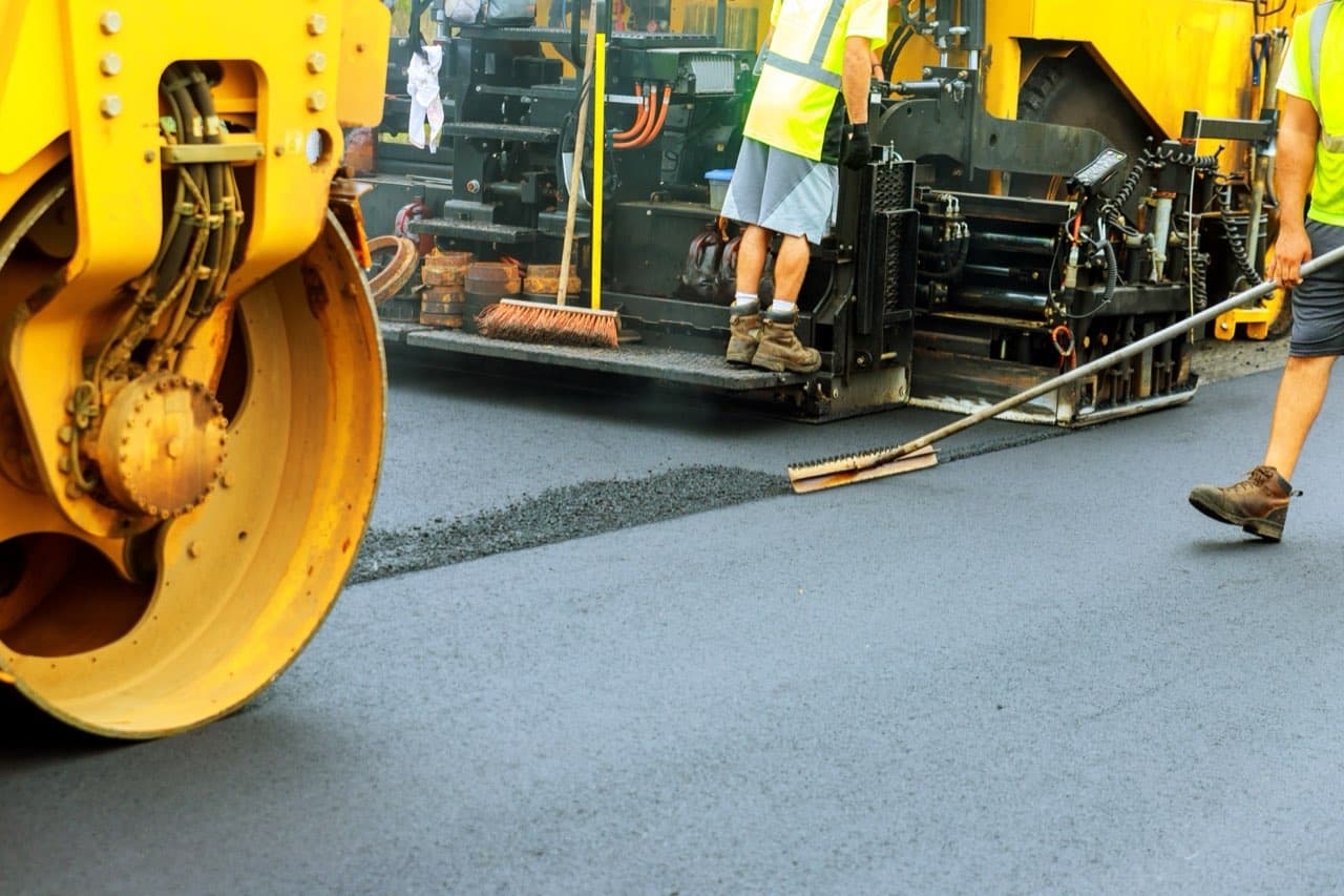 Paving crew laying and rolling fresh hot asphalt
